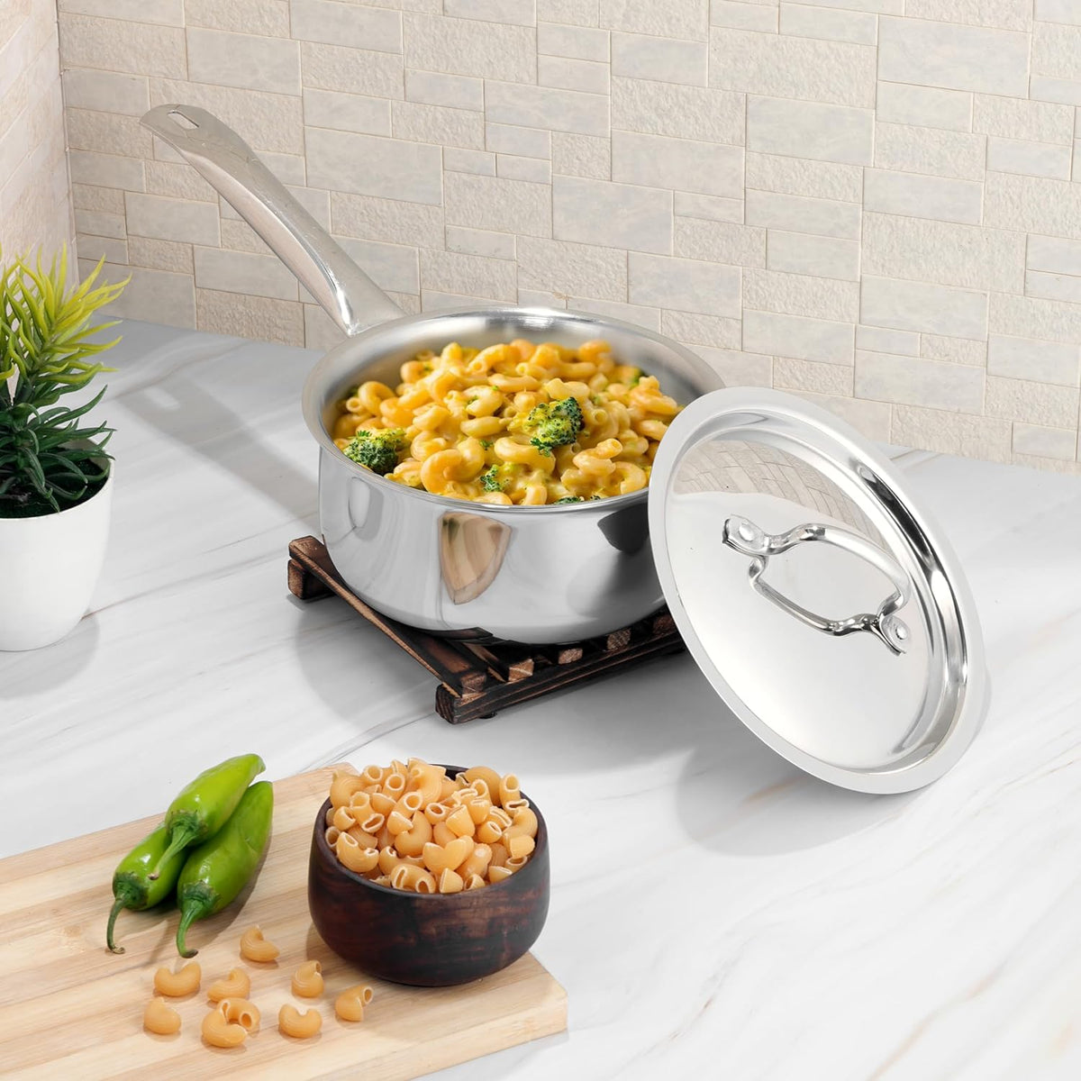 Stainless steel pot with macaroni and broccoli on a kitchen counter